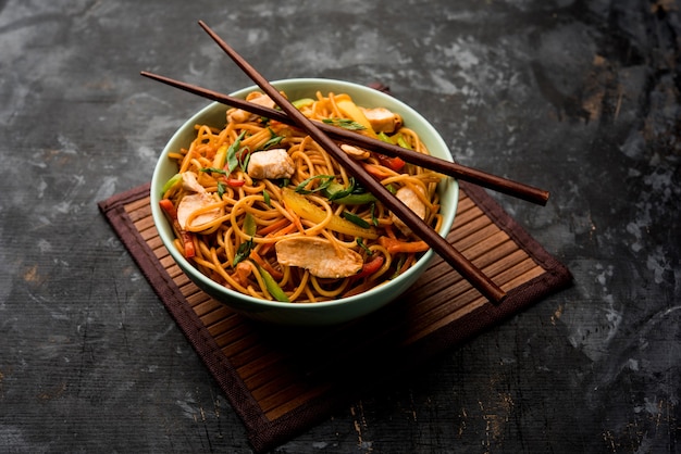 Poulet Hakka ou nouilles Schezwan servies dans un bol avec des baguettes. mise au point sélective