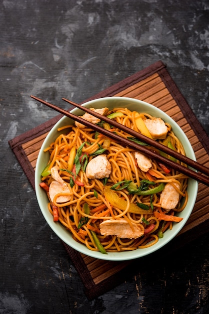 Poulet Hakka ou nouilles Schezwan servies dans un bol avec des baguettes. mise au point sélective