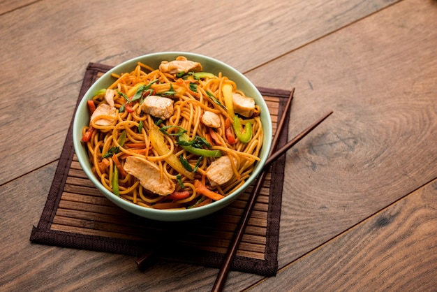 Poulet Hakka ou nouilles Schezwan servies dans un bol avec des baguettes. mise au point sélective