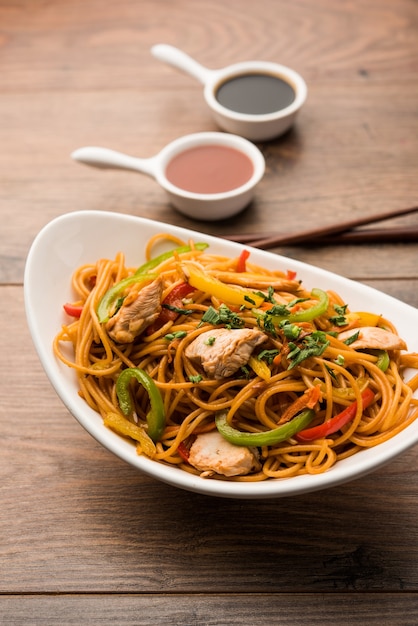 Poulet Hakka ou nouilles Schezwan servies dans un bol avec des baguettes. mise au point sélective