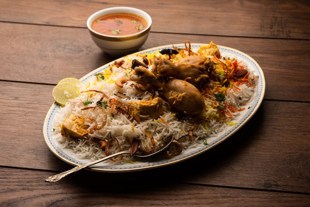 Poulet indien Biryani servi dans un bol en terre cuite avec du yaourt sur fond blanc. mise au point sélective