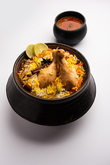 Poulet indien Biryani servi dans un bol en terre cuite avec du yaourt sur fond blanc. mise au point sélective