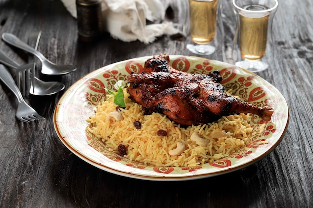 Poulet Kabsa ou poulet Biryani sur fond de bois Kabsa est un plat de cuisine saoudien traditionnel qu'il cuisine avec du riz basmati Poulet Épices Tomates Noix Raisins secs