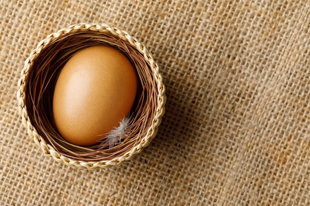 Poulet ou œuf de poule dans un panier en osier sur un sac