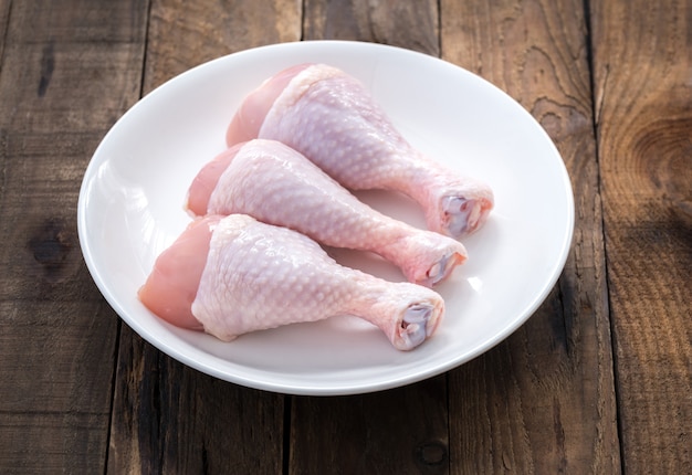 Poulet pilon cru sur assiette blanche