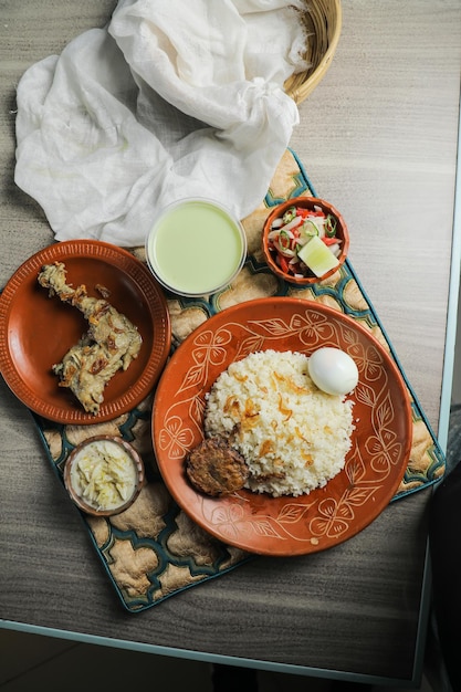Poulet pulao biryani Morog Pulao Combo avec salade borhani et Chui Pitha servi dans un plat isolé sur un tapis vue de dessus de la nourriture indienne et bangladaise
