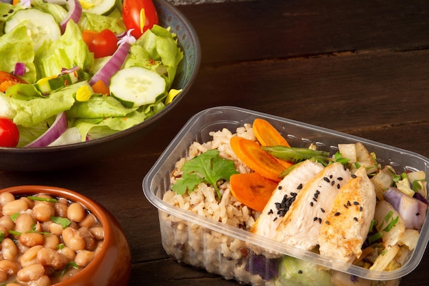 Poulet et riz emballés dans une boîte à déjeuner en bois sur le fond de l'avant.