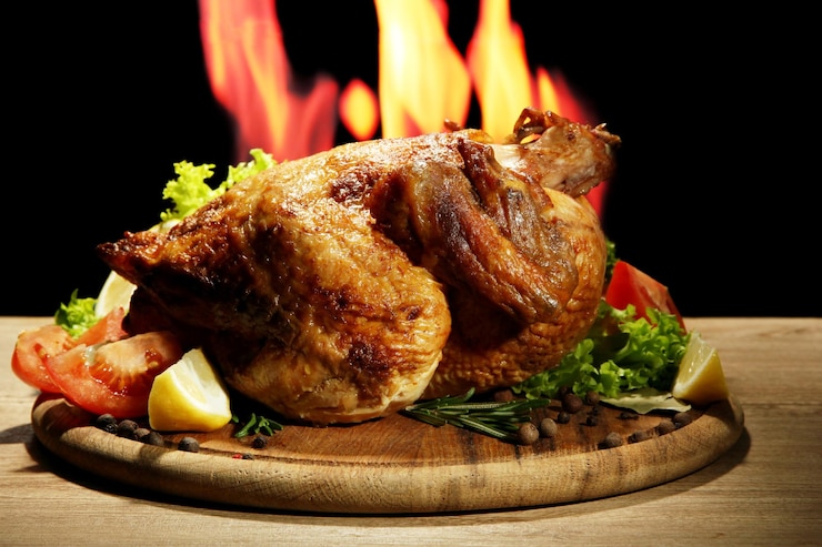 Photo poulet rôti entier avec des légumes sur une assiette sur fond de flamme
