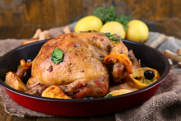 Poulet rôti entier avec des légumes sur pan sur fond de bois