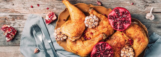 Poulet rôti à la grenade et à l'ail sur fond de bois Dîner entre amis ou en famille Table de Noël festive Vue de dessus Plat traditionnel de célébration de vacances de Thanksgiving ou de Friendsgiving