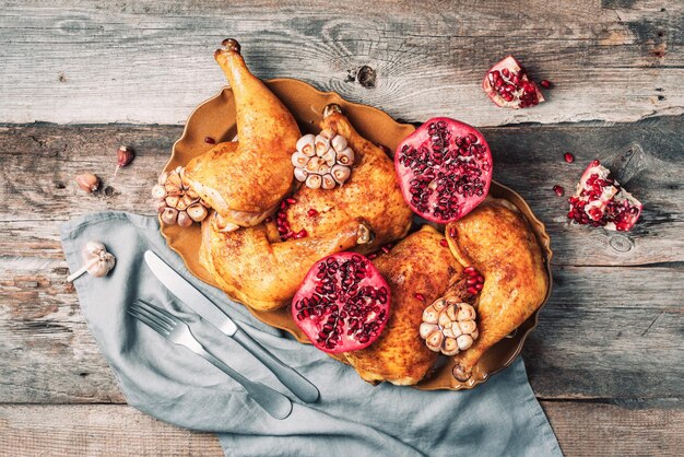 Poulet rôti à la grenade et à l'ail sur fond de bois Dîner entre amis ou en famille Table de Noël festive Vue de dessus Plat traditionnel de célébration de vacances de Thanksgiving ou de Friendsgiving