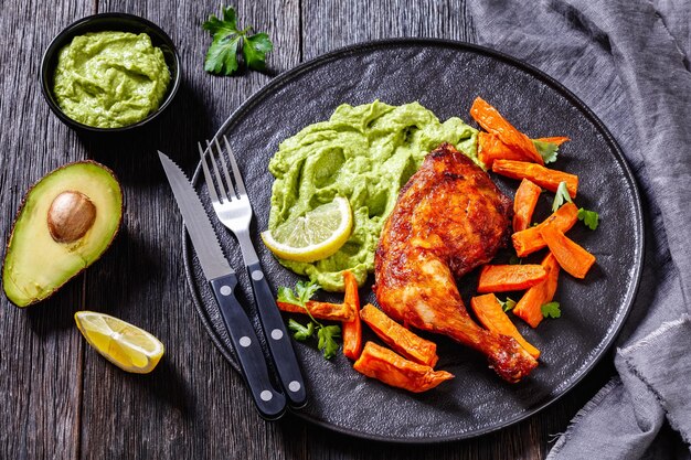 Photo poulet rôti avec sauce wasacaca de poivre vert avocat et herbes et chips de patate douce sur plaque noire sur table en bois vue horizontale d'en haut