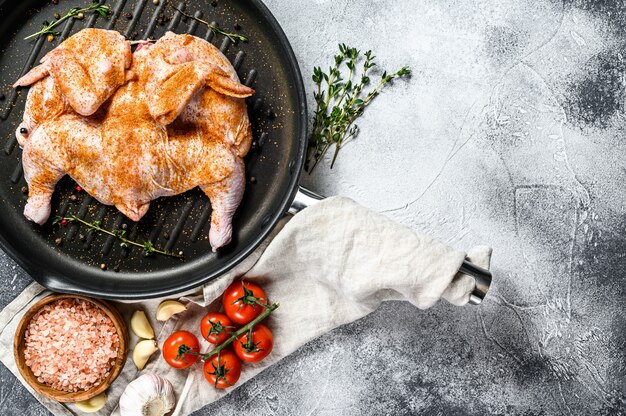 Poulet tabaka cru dans une poêle. Vue de dessus.