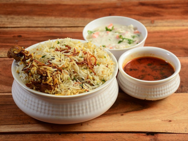 Poulet traditionnel Hyderabadi dum Biryani fait de riz Basmati cuit avec des épices masala servi avec de la raïta à l'oignon et de la mise au point sélective de Salan