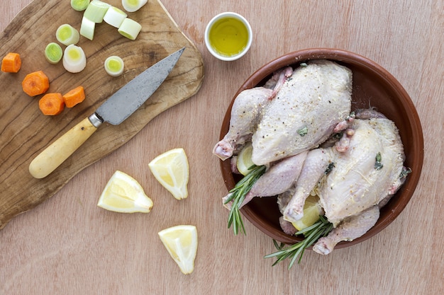 Poulets coquelets crus préparés pour rôtir avec des légumes et des herbes