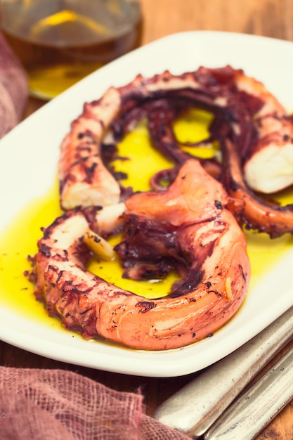 Poulpe grillé à l'ail sur plat blanc sur fond de bois