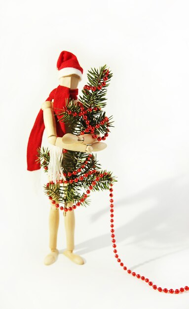 La poupée en bois décore l'arbre de Noël et le mannequin du nouvel an en chapeau et écharpe de père Noël rouges
