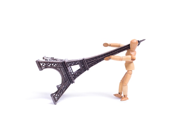 Photo une poupée en bois pousse une statue de la tour eiffel.