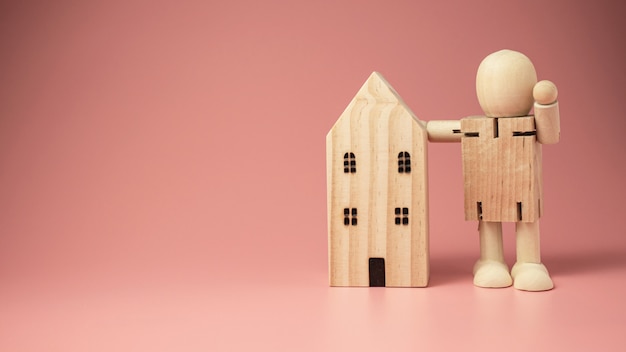 poupée en bois se dresse à côté de la maison.