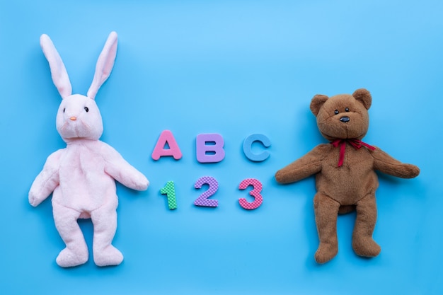 Poupée lapin et ourson avec alphabet anglais et chiffres sur fond bleu. Concept de l'éducation
