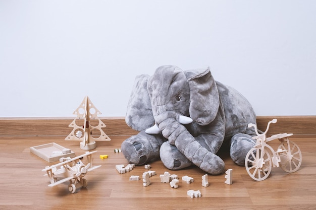 Poupée pelucheuse mignonne d'éléphant et jouets en bois sur le plancher