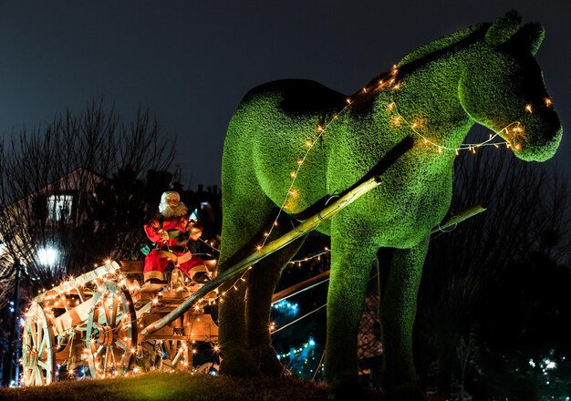 Poupée Père Noël sur un traîneau avec un cheval décoré de lumières pour briller la nuit