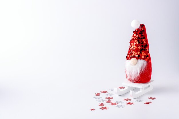 Poupée Père Noël sur un traîneau avec des confettis sur un fond blanc pour le texte