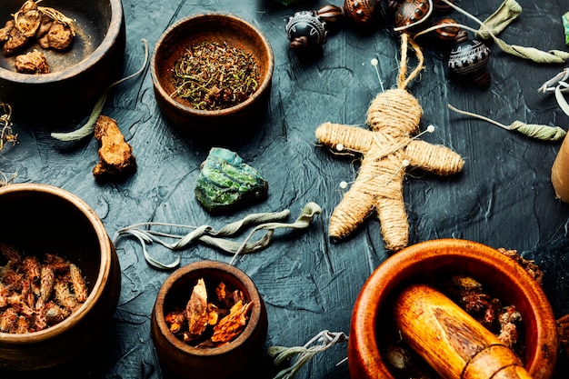 Poupée vaudou, herbes magiques et attributs de sorcellerie sur une vieille table