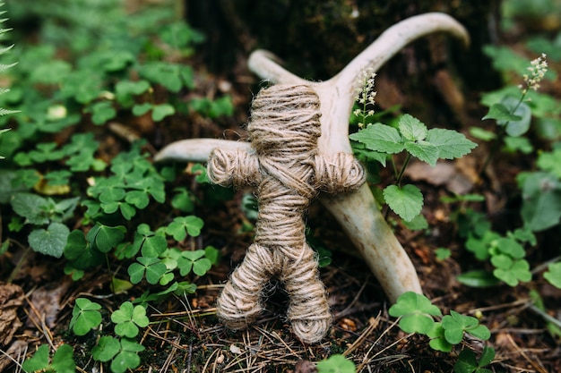 Une poupée vaudou tissée de fils et d'os lors d'un rituel dans une forêt mystérieuse