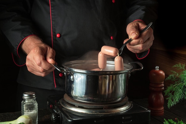 Pour un délicieux petit déjeuner besoin de faire cuire de délicieuses saucisses au lait Chef dans la cuisine pendant le travail