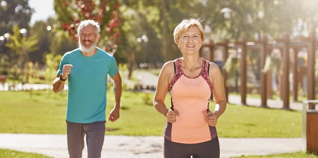 Pour une meilleure santé, un couple familial mature et actif en vêtements de sport a l'air heureux tout en courant ensemble dans