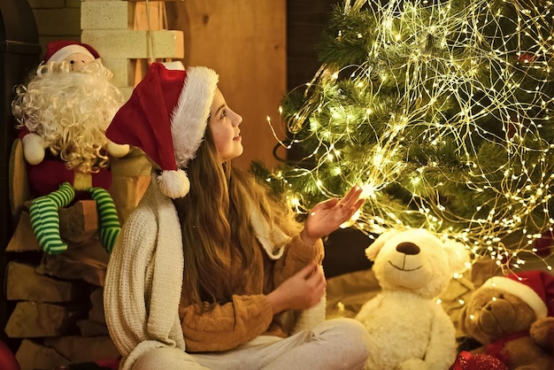 Pour le sapin de noël du père noël avec des lumières belle et confortable chambre petite fille attendre la fête de noël du nouvel an est sur une enfance heureuse cette nuit d'hiver être un jouet pour enfant brillant présente l'enfant du père noël à l'arbre de noël