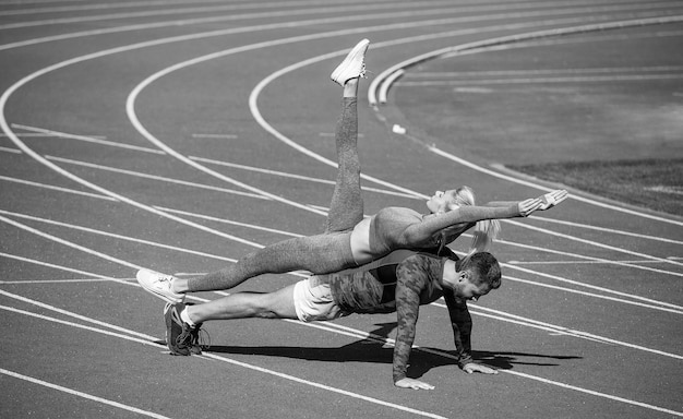 Pousser vers le haut l'exercice de la planche de défi d'entraînement pour la santé des muscles du tronc est une aide à la vie et un soutien pour les sportifs, homme et femme, entraîneur de sport, couple de fitness s'entraînant ensemble