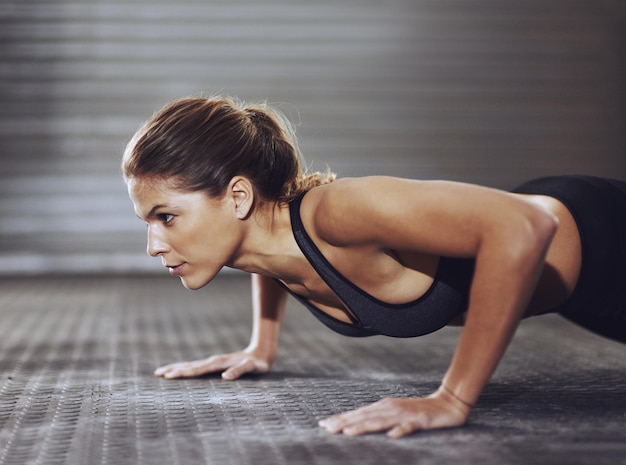 Poussez-vous, personne ne le fera pour vous Photo recadrée d'une jeune femme faisant des pompes à la salle de sport