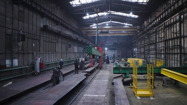 La poutre métallique est déplacée sur des chaînes dans l'usine. La poutre en acier suspendue sur des chaînes est traînée à l'usine.