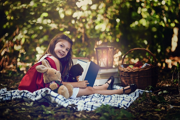 Pouvez-vous deviner quelle est mon histoire préférée Portrait d'une petite fille lisant un livre avec ses jouets dans les bois