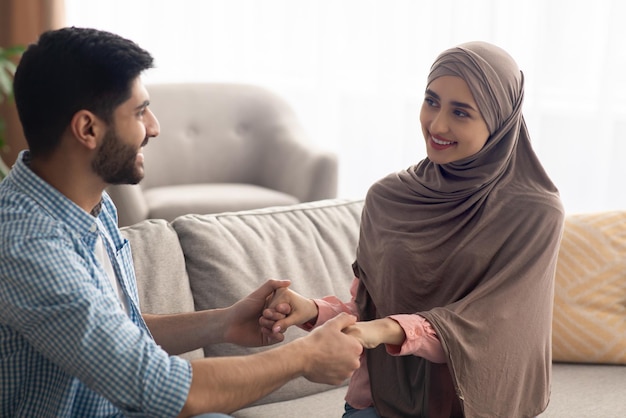 Époux islamiques se tenant la main en souriant à la maison