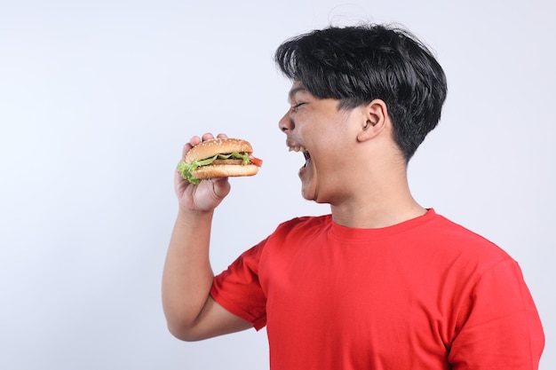 POV Jeune homme asiatique excité à manger un burger isolé sur un fond blanc