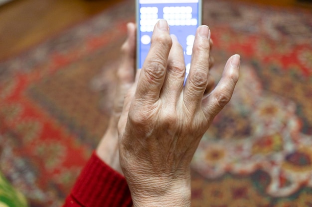 POV de la main d'une vieille dame jouant sur un smartphone