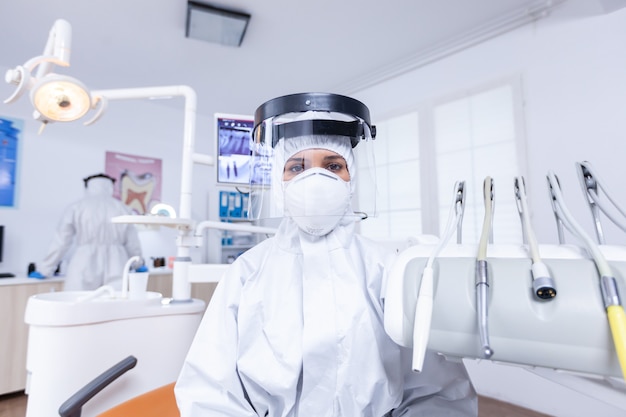 Pov patient de dentiste expliquant le traitement des dents habillé en costume de protection covid. Stomatolog portant un équipement de sécurité contre le coronavirus lors du contrôle des soins de santé du patient.