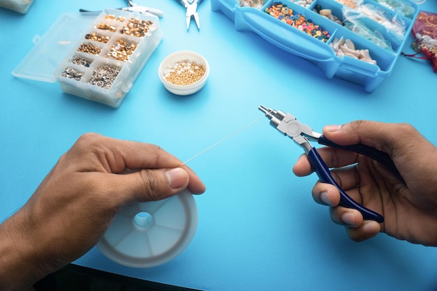 Pov Prise de vue à la première personne des mains utilisant une pince et une ficelle métallique comme outil pour fabriquer des bijoux faits maison