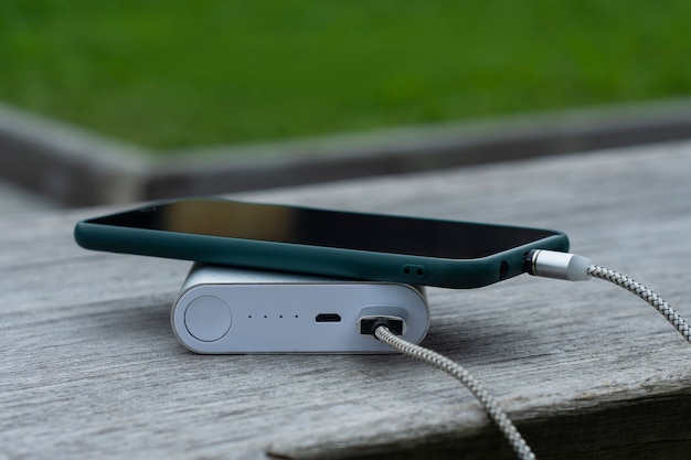 Power Bank charge un smartphone sur un banc en bois dans le parc.