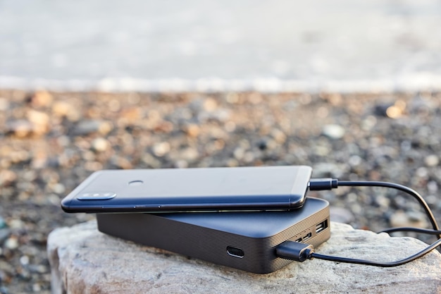 Powerbank charge le téléphone sur la plage au bord de la mer