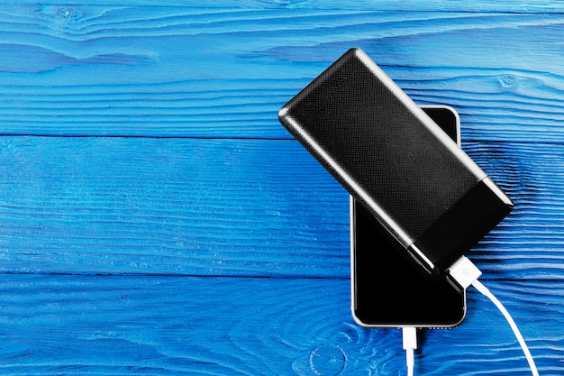 Powerbank facture un smartphone isolé sur une surface en bois bleue