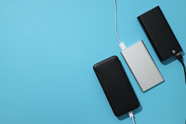 Powerbanks avec cordons sur fond bleu, espace pour le texte