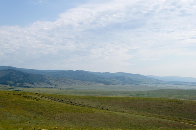 Des prairies d'un vert éclatant s'étendent au loin jusqu'aux montagnes bleues Le soleil brille de mille feux