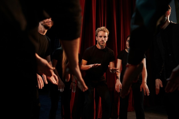 Pratique en cours Groupe d'acteurs en vêtements de couleur foncée en répétition au théâtre