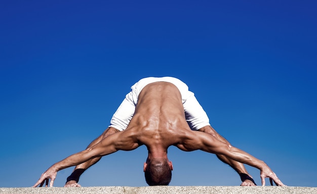 La pratique du yoga aide à trouver l'harmonie et l'équilibre. Homme pratiquant le yoga fond de ciel bleu. Atteint la tranquillité d'esprit. Concept de méditation et de yoga. Le yoga aide à trouver l'équilibre. Pratiquez les asanas en extérieur.