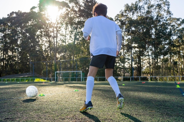 Photo pratique de football d'enfants par un jour ensoleillé cônes de couleur délimitant la pratique pour utiliser le ballon