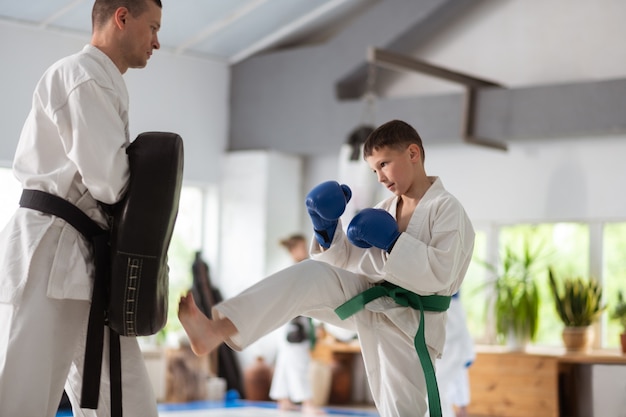 Pratiquer des coups de poing. Garçon actif aux cheveux noirs portant des gants de protection pratiquant ses coups de poing